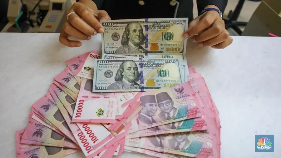 Petugas menunjukkan uang pecahan dolar AS dan rupiah di gerai penukaran mata uang asing di tempat penukaran uang PT Ayu Masagung, Jakarta, Senin (18/11/2024).